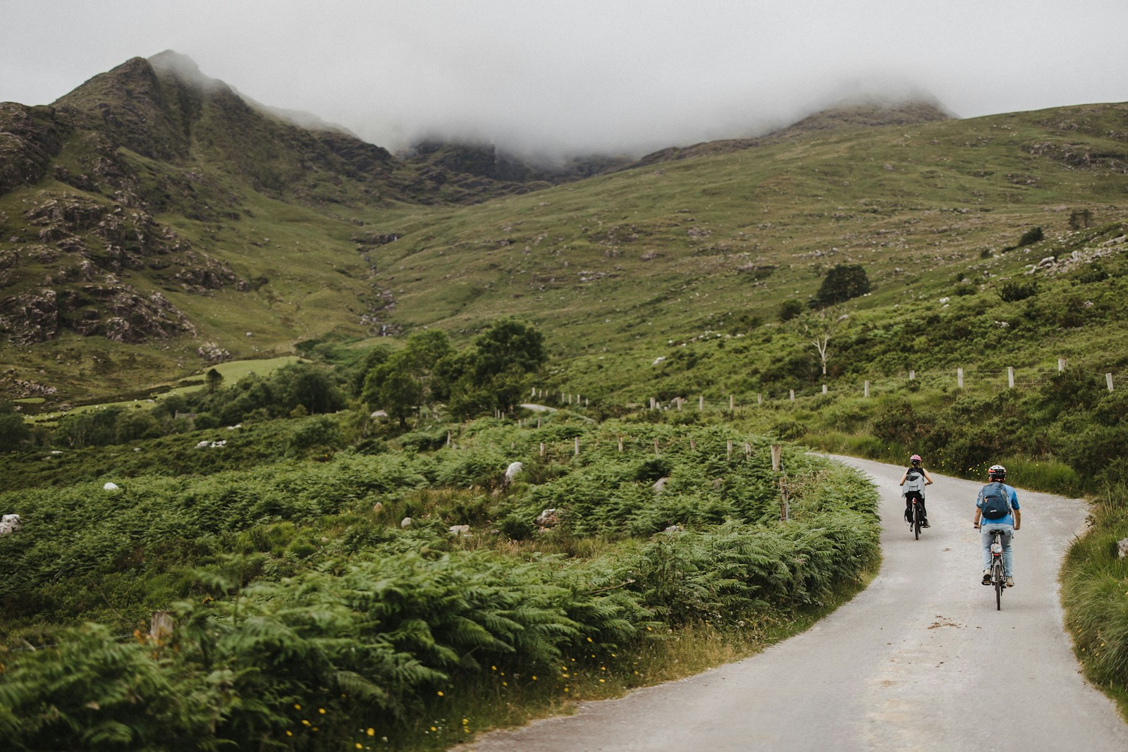 Two cyclists on the winding road through the green Gap of Dunloe in Ireland
